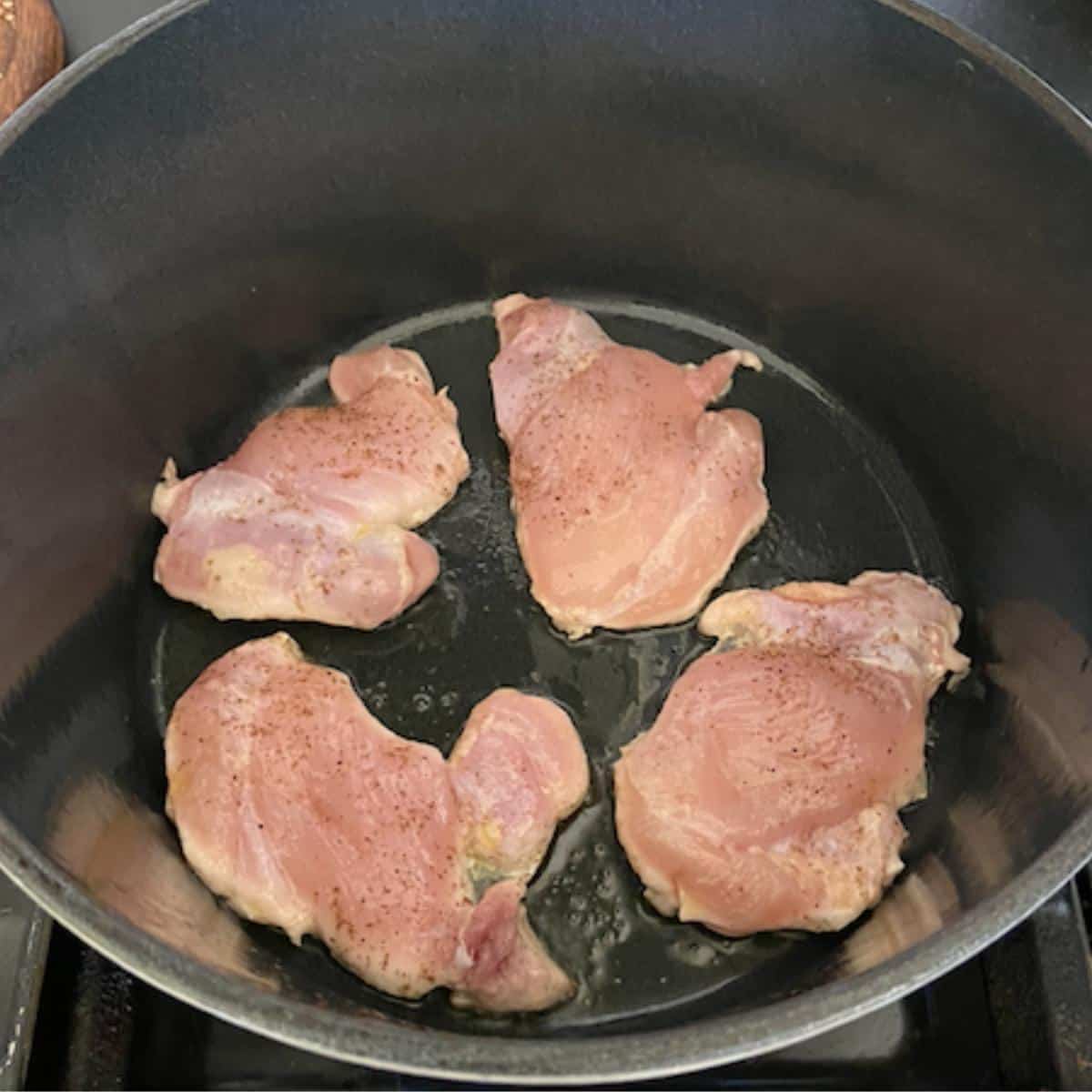 chicken thighs cooking in dutch oven
