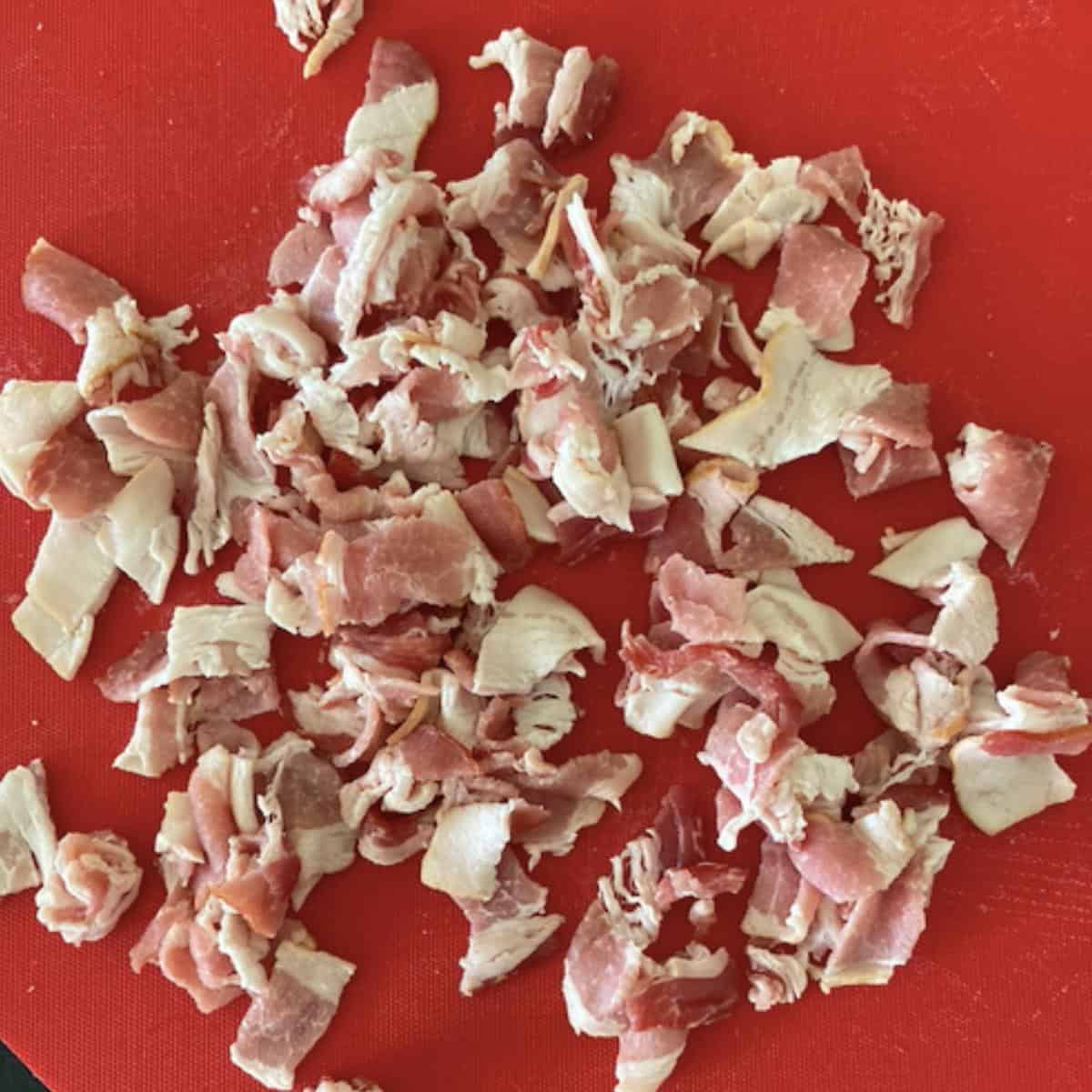 bacon cut into smaller pieces on red cutting board