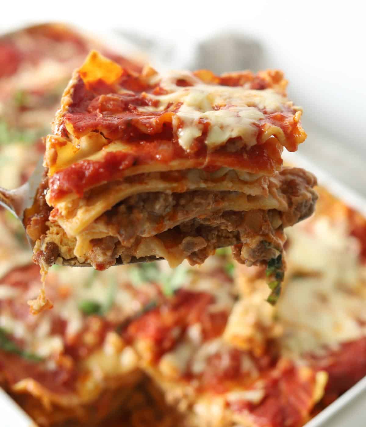 slice of lasagna being held over the tray of lasagna al forno
