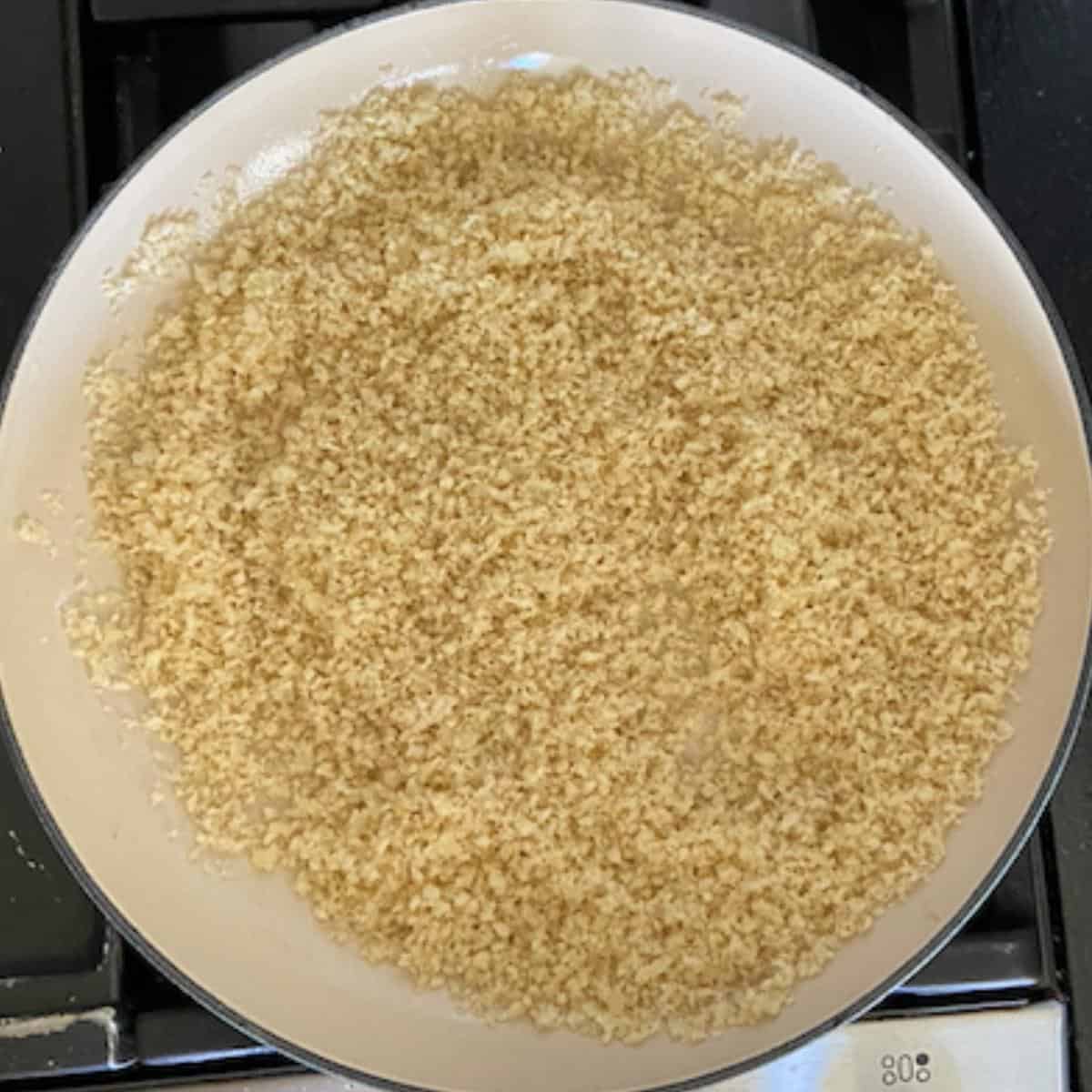 panko cooking in skillet with garlic butter