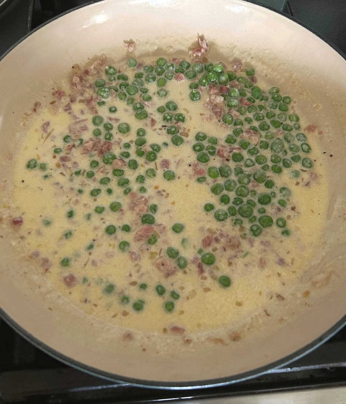 Peas and pancetta cooking in cream sauce.