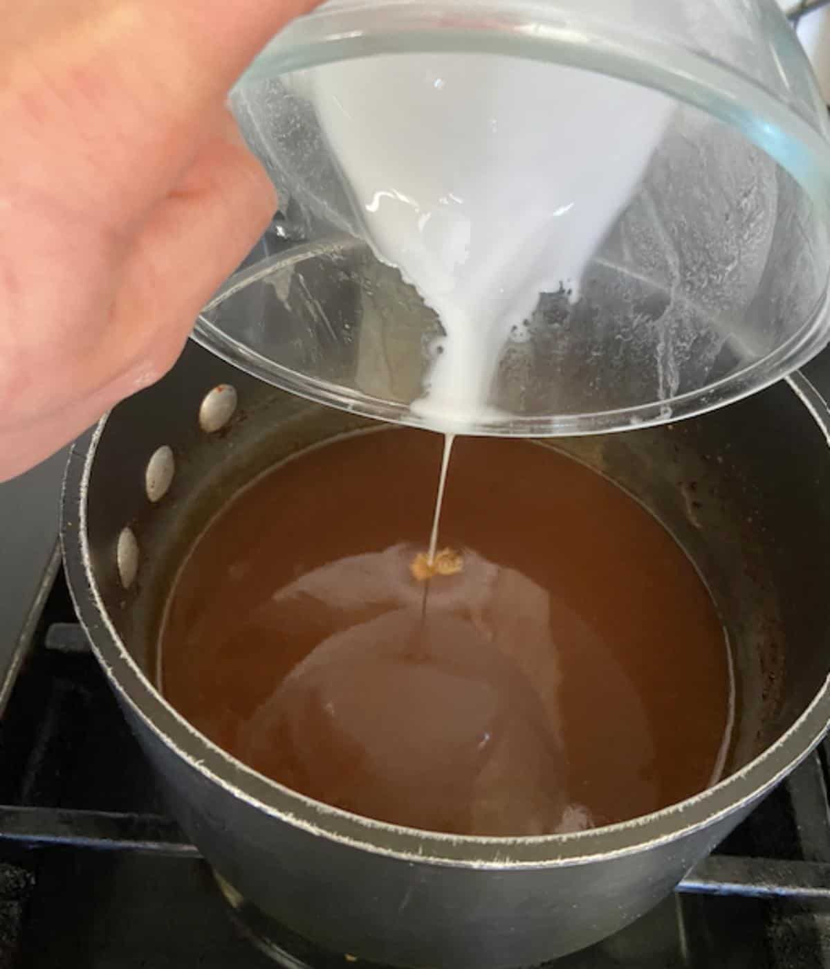 hand pouring cornstarch mixture into pineapple ham glaze