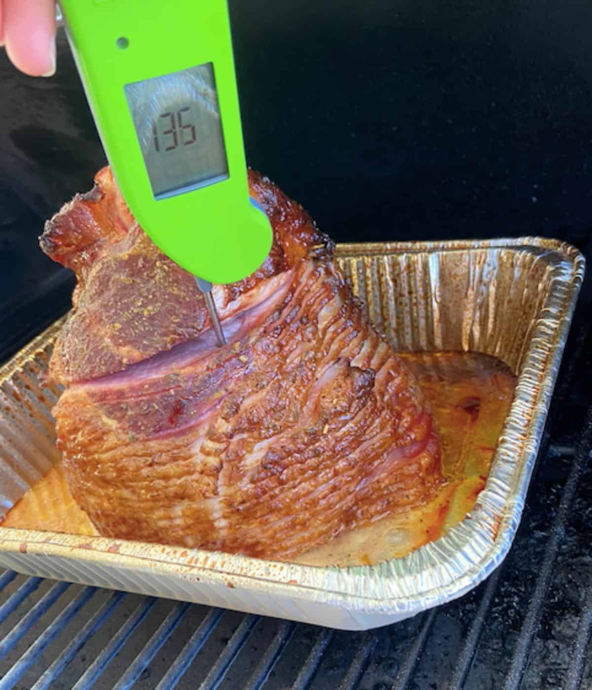 thermometer showing a reading of 135 from the ham in smoker