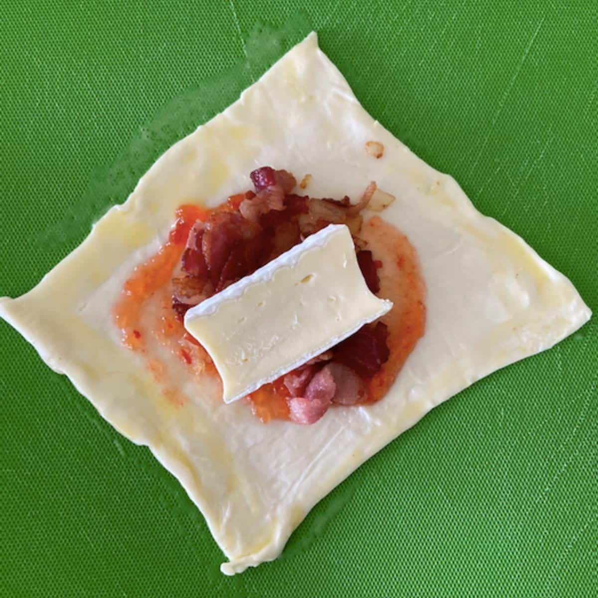 puff pastry square filled with pepper jelly, bacon, onion, and brie