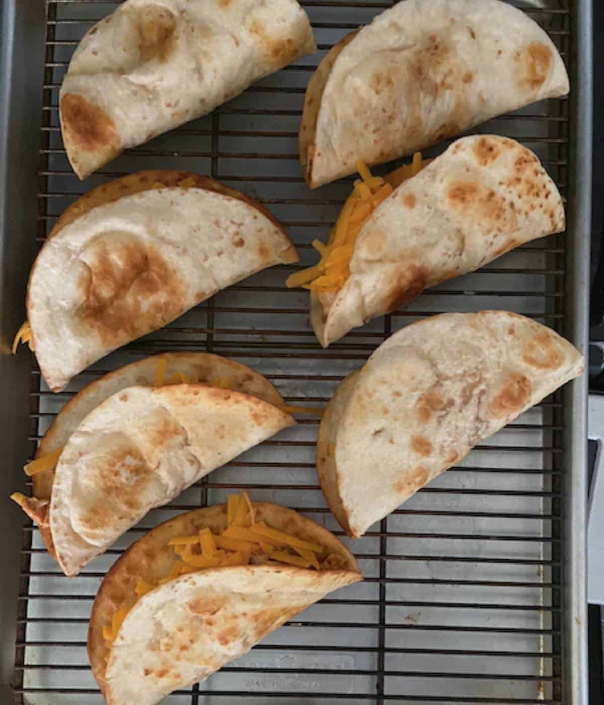 tacos on cookie sheet with rack ready to bake