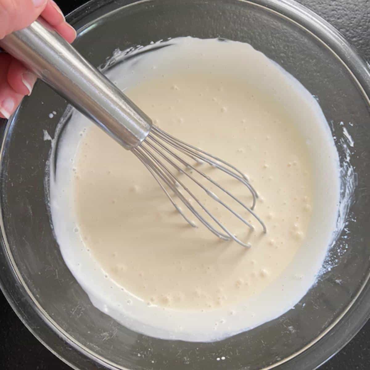 macaroni salad sauce with hand holding whisk