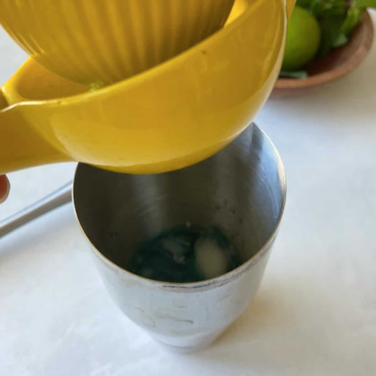 squeezing lime juice into shaker over mint