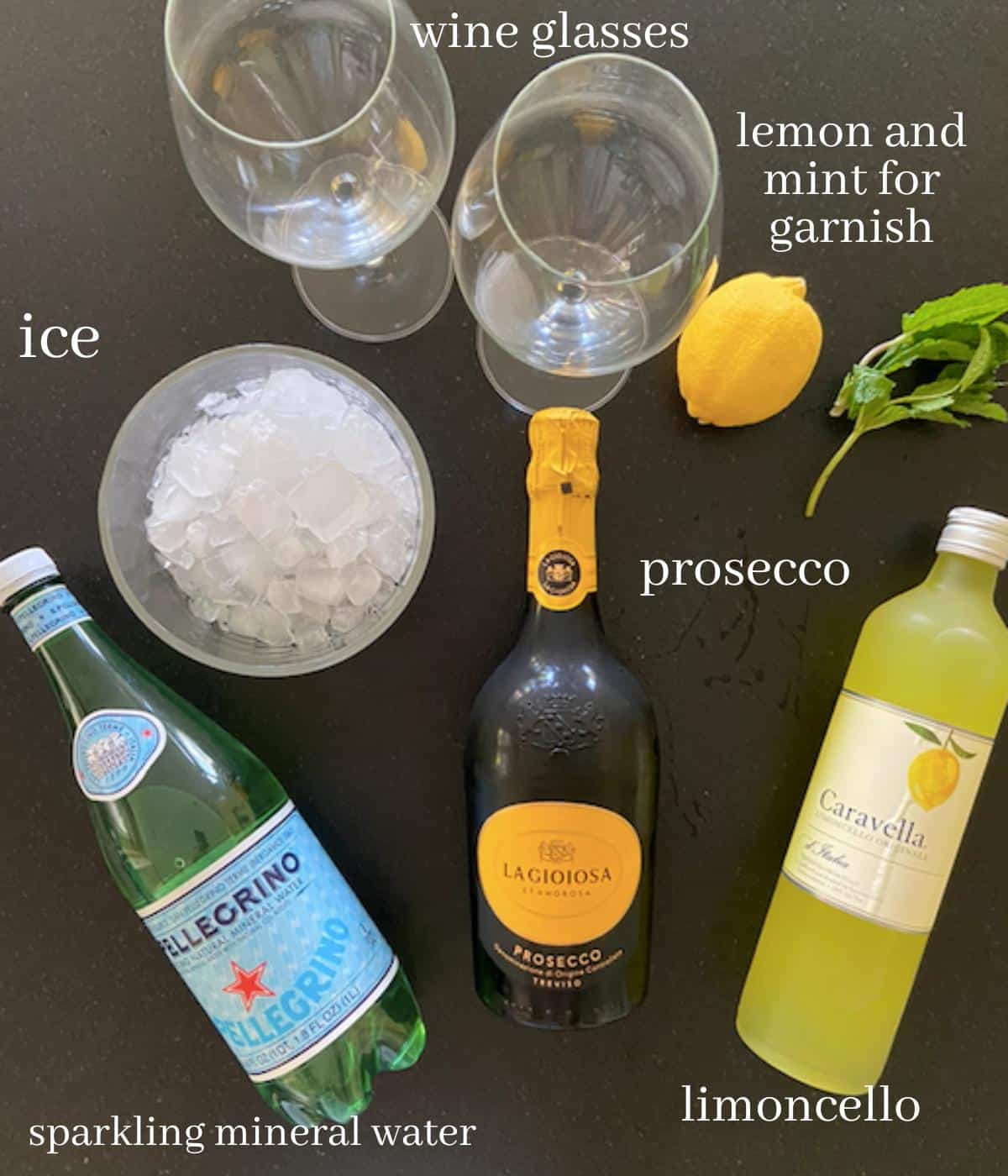 ingredients for limoncello spritz on black countertop with text