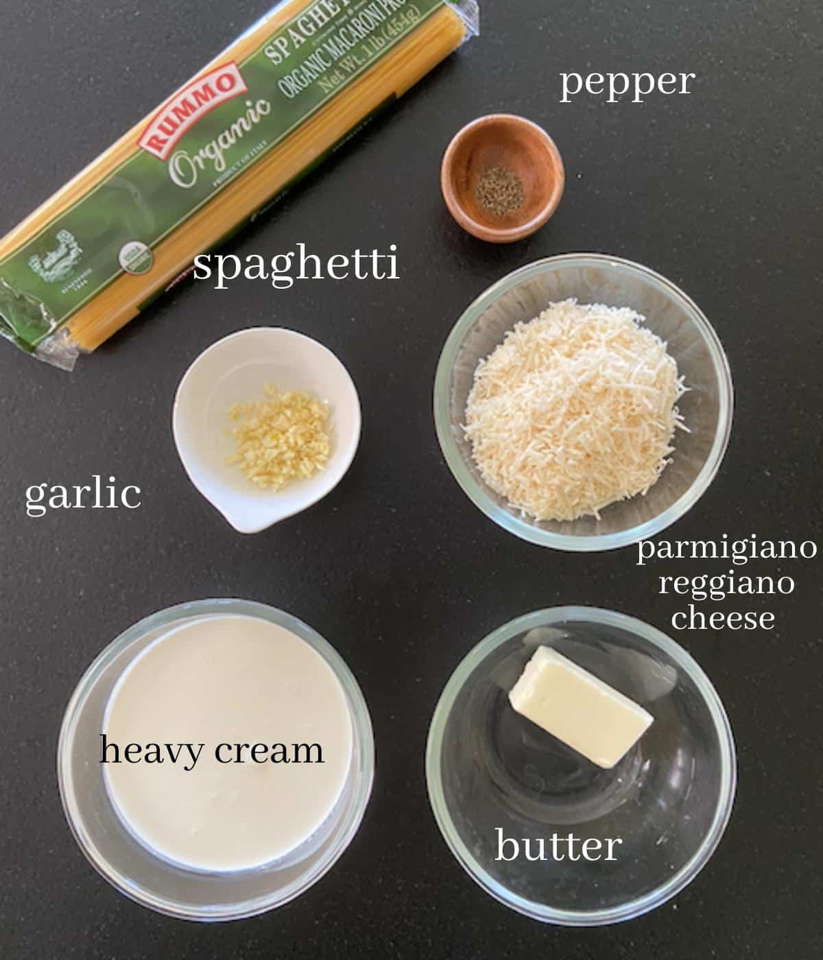spaghetti alfredo ingredients on black countertop