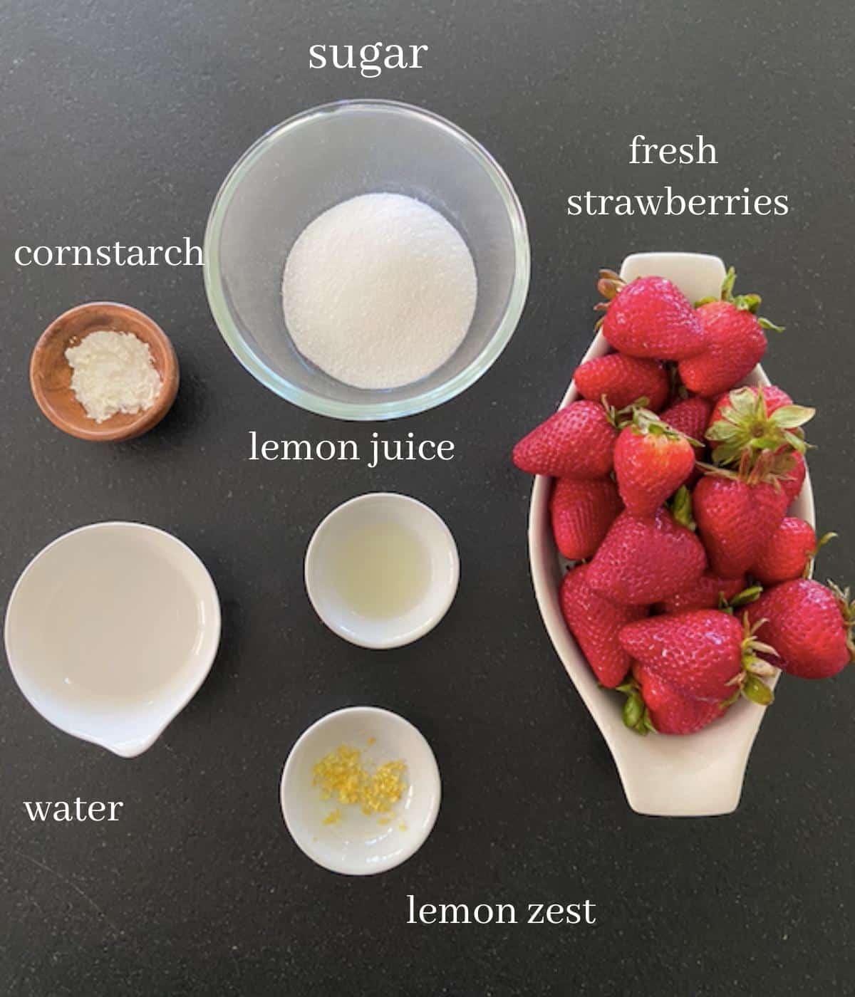 ingredients for strawberry sauce on black countertop with text
