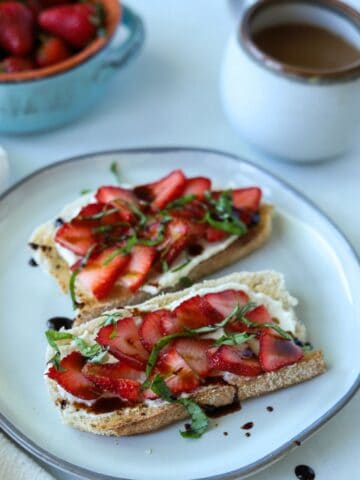 strawberry ricotta toast on plate with coffee in background