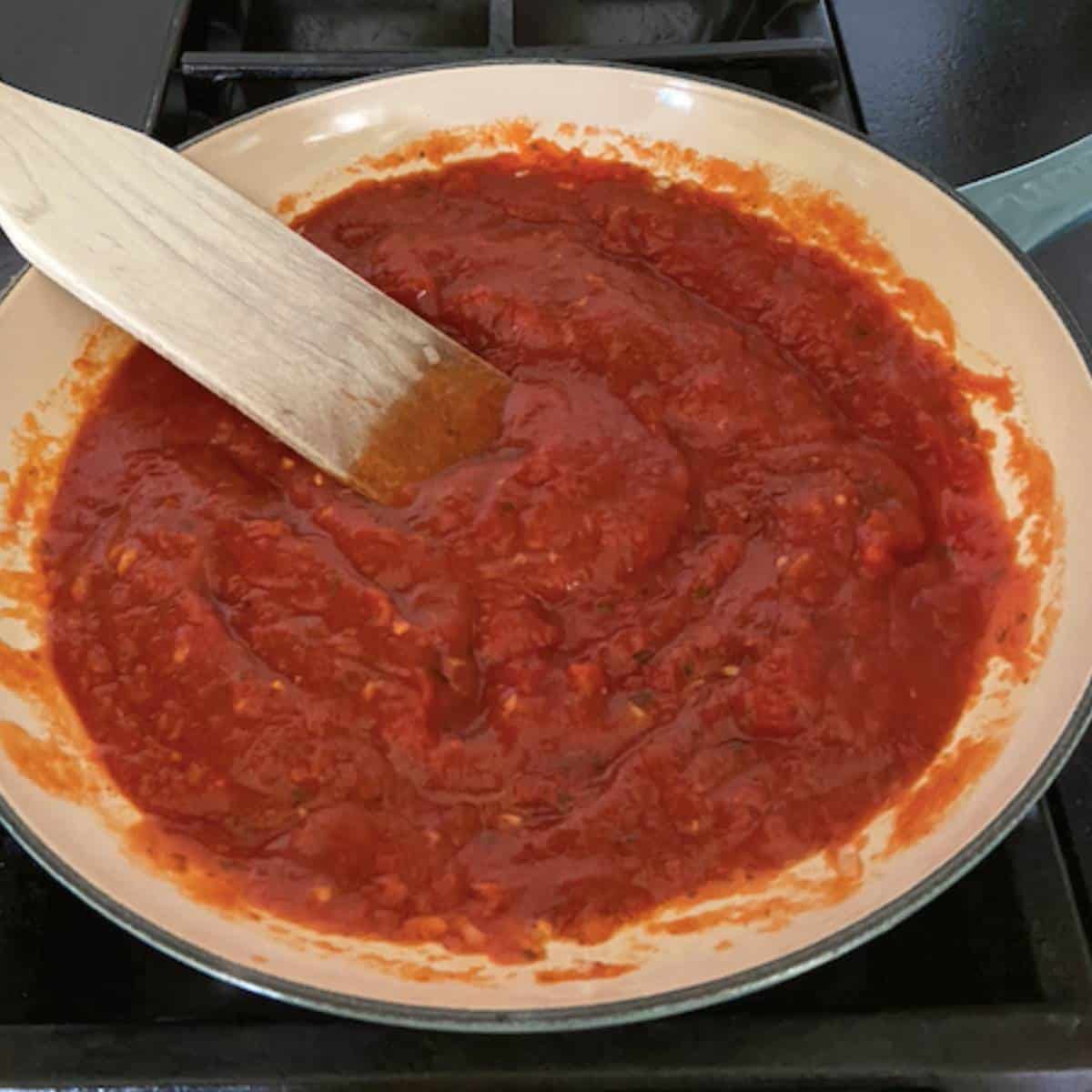 Marinara sauce with wooden spoon in skillet.