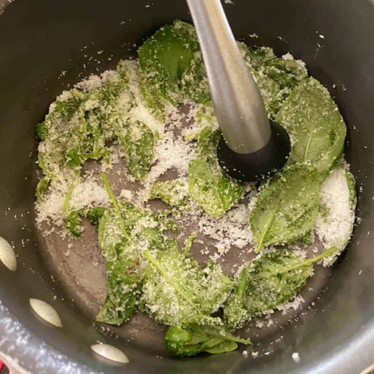 Muddling basil with sugar in pot.