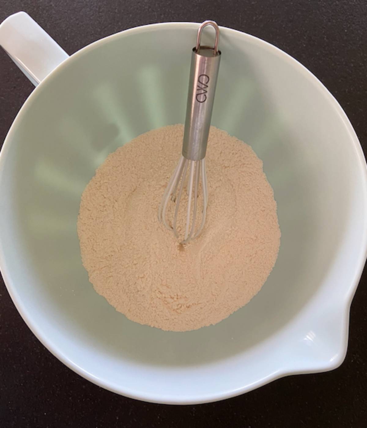 Dry ingredients in blue bowl with whisk.