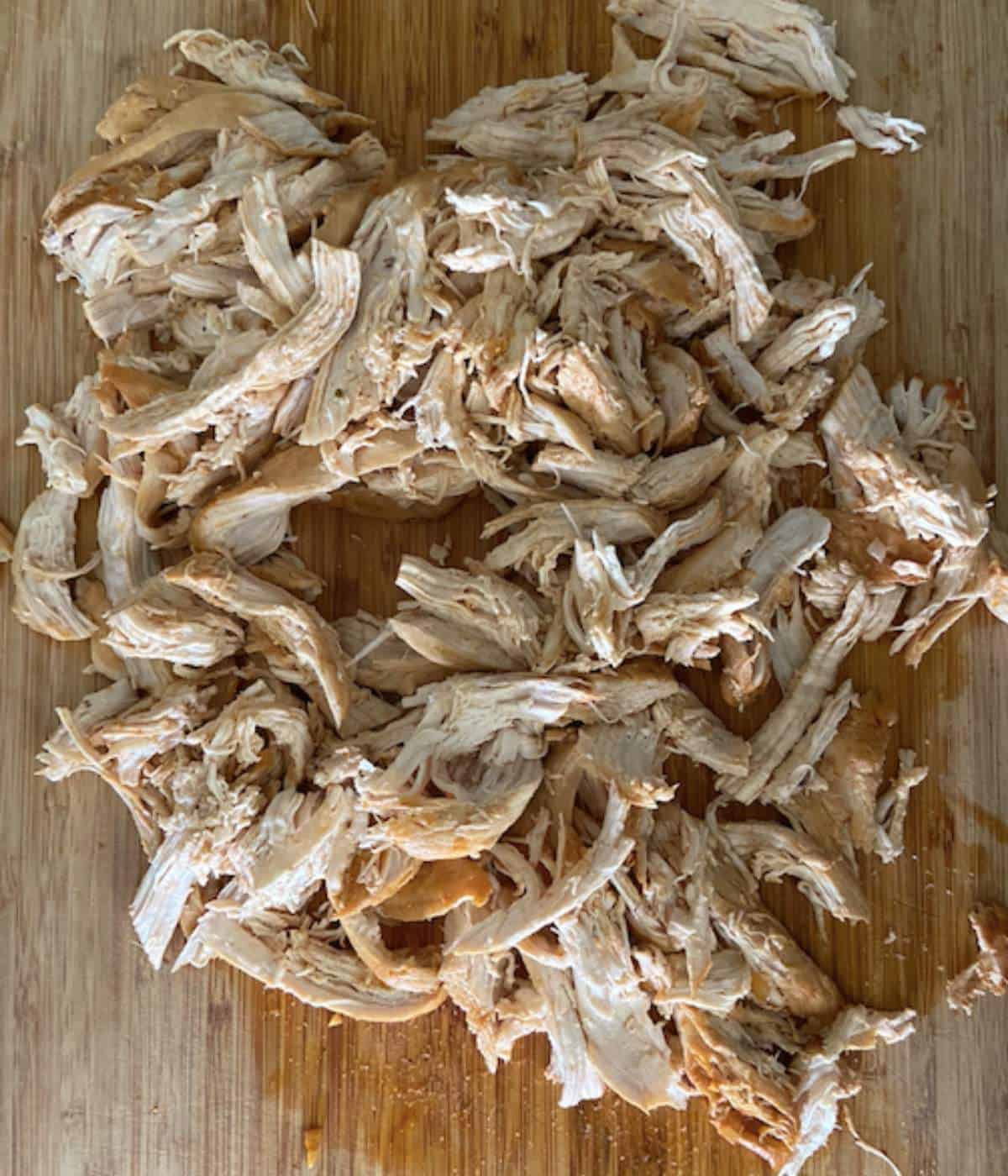 Pulled chicken on cutting board.