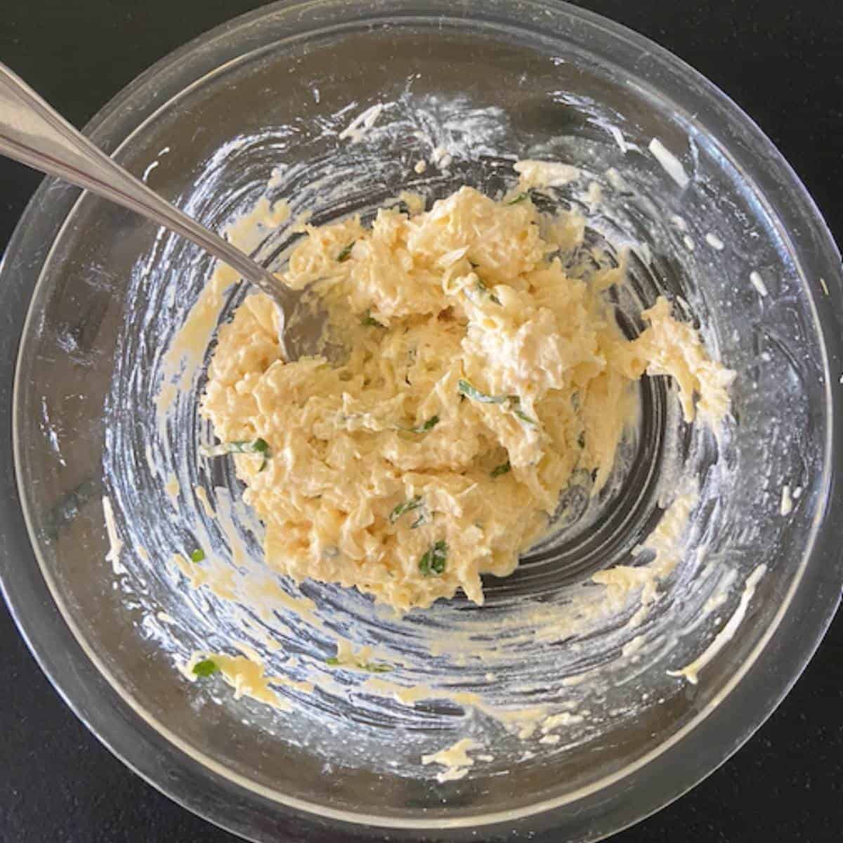 Four cheese mixture with egg mixed together in glass bowl.