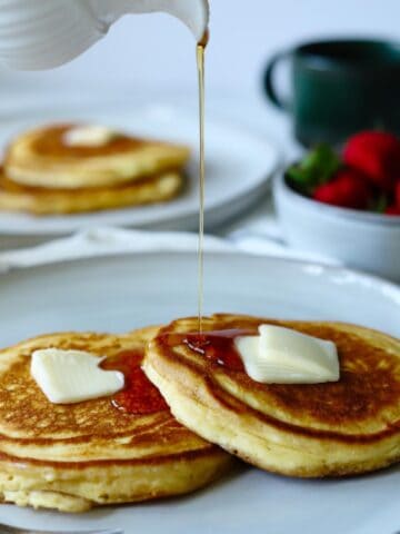 Syrup pouring over pancakes on gray plate.