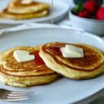 Pancakes with butter on gray plate with syrup pouring over.
