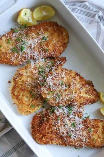 Chicken Romano on white dish topped with pecorino romano cheese.