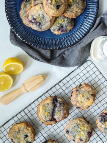 Lemon blueberry cookies on baking tray with lemon and juicer.