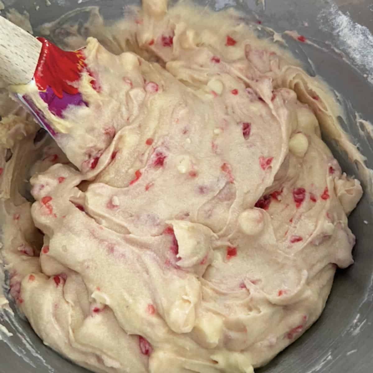 Raspberries and white chocolate chips mixed into batter in mixer.