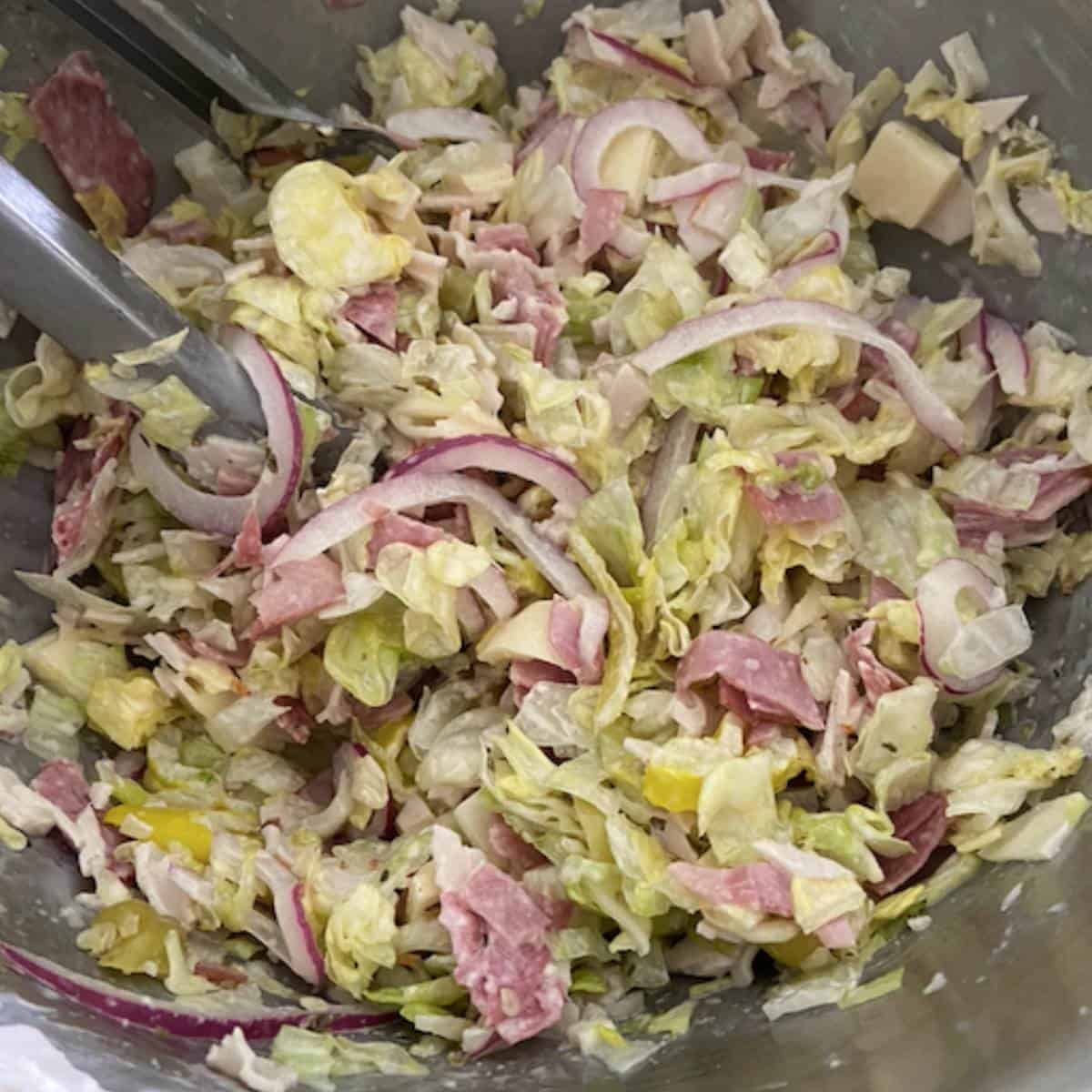 Tossing grinder salad with tongs.