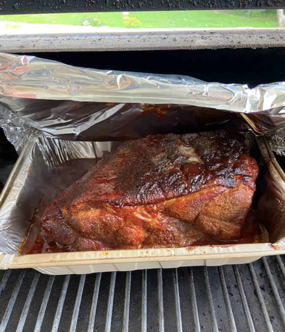 BBQ sauce, brown sugar, and butter added to pork butt in smoker.