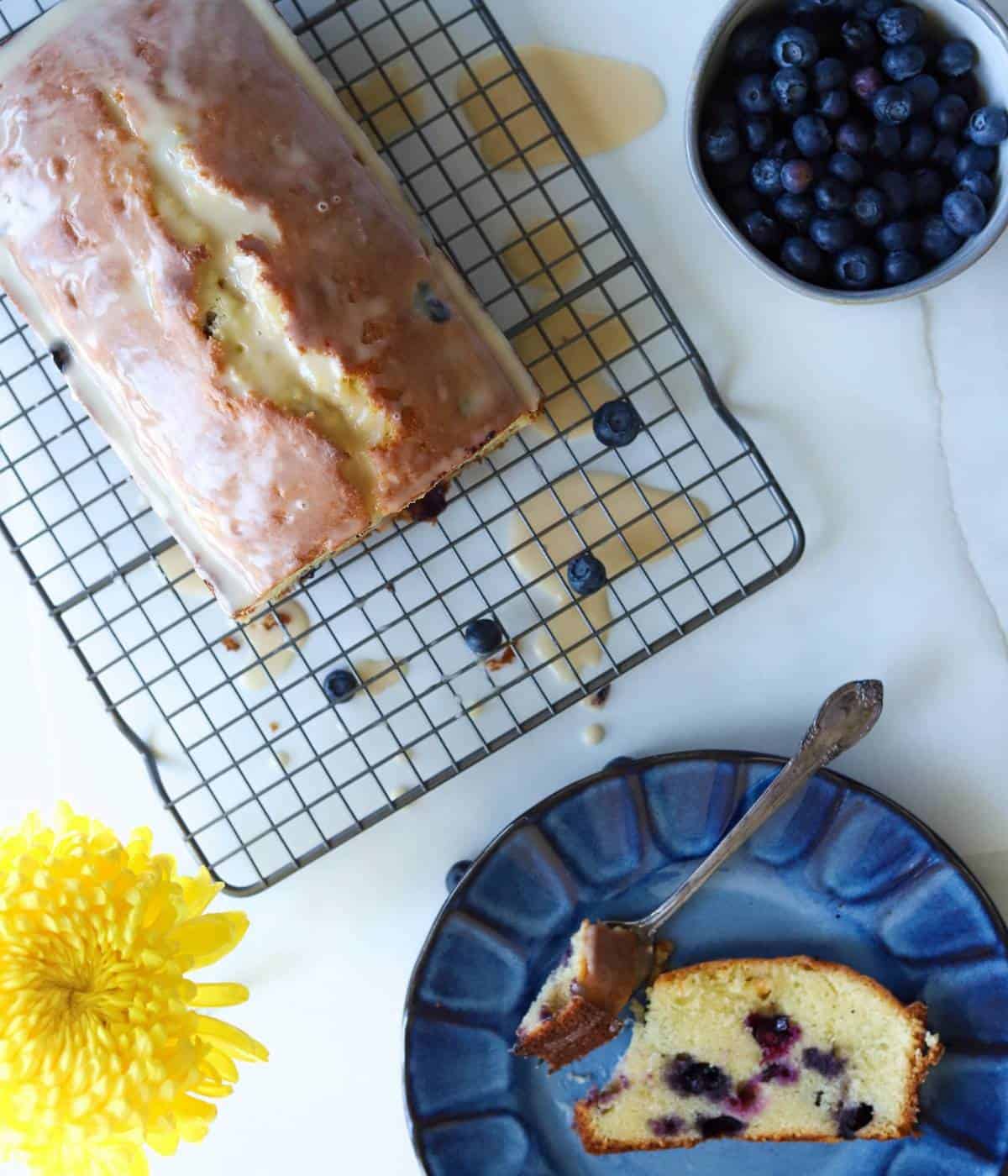 Blueberry Pound Cake on rack with slice on blue plate.