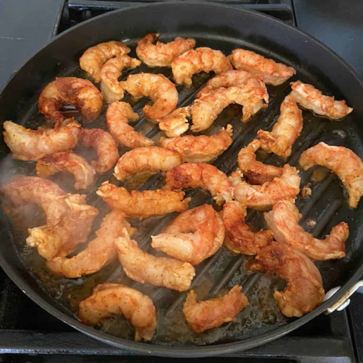 Shrimp pan frying on grill pan.