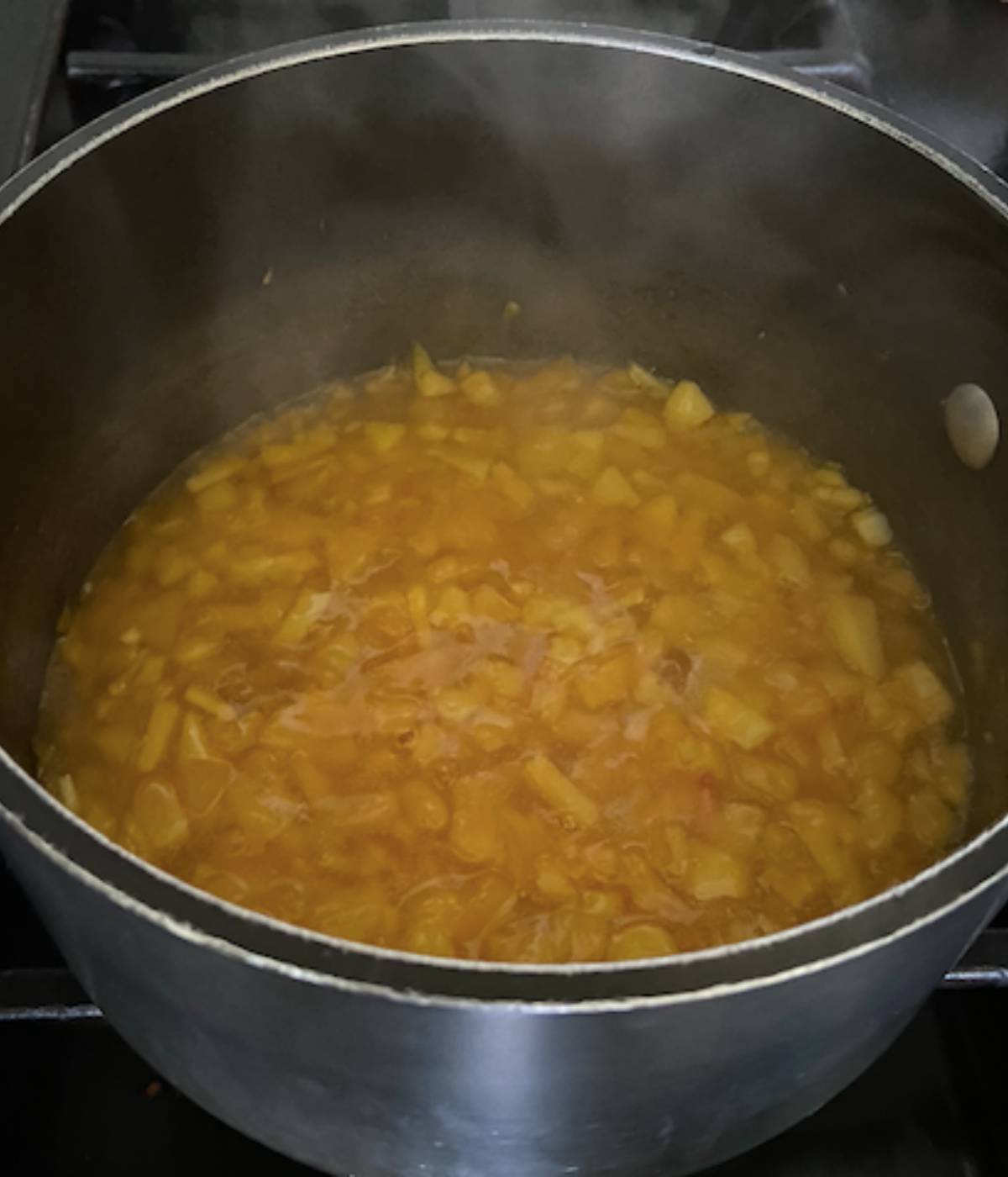 Peach mango filling cooking in pot on stovetop.