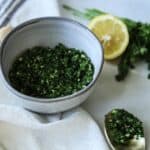 Gremolata sauce in gray bowl with lemon in background.