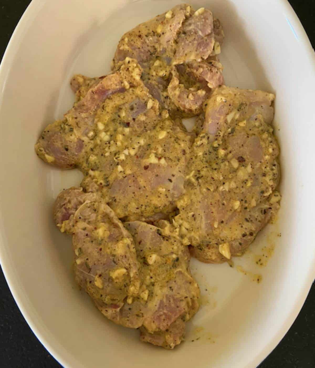 Raw chicken thighs in casserole dish.