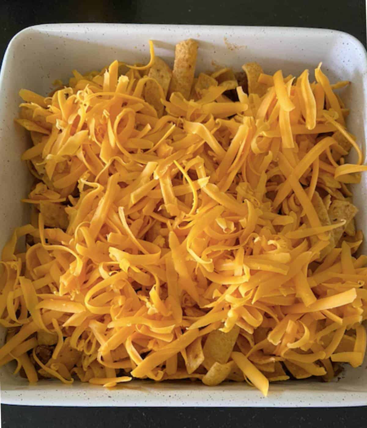Frito pie topped with cheese.