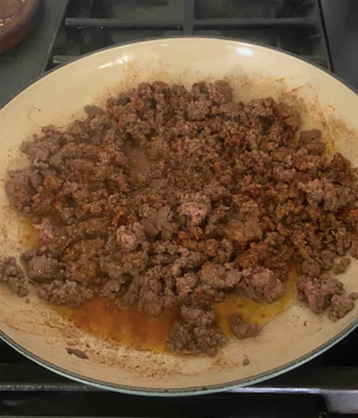 Ground beef cooking in skillet.