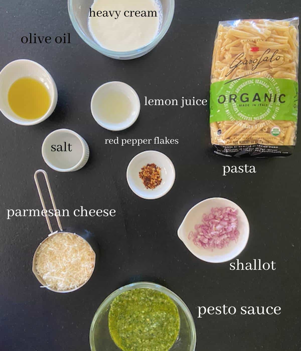 Ingredients for creamy pesto pasta on countertop.