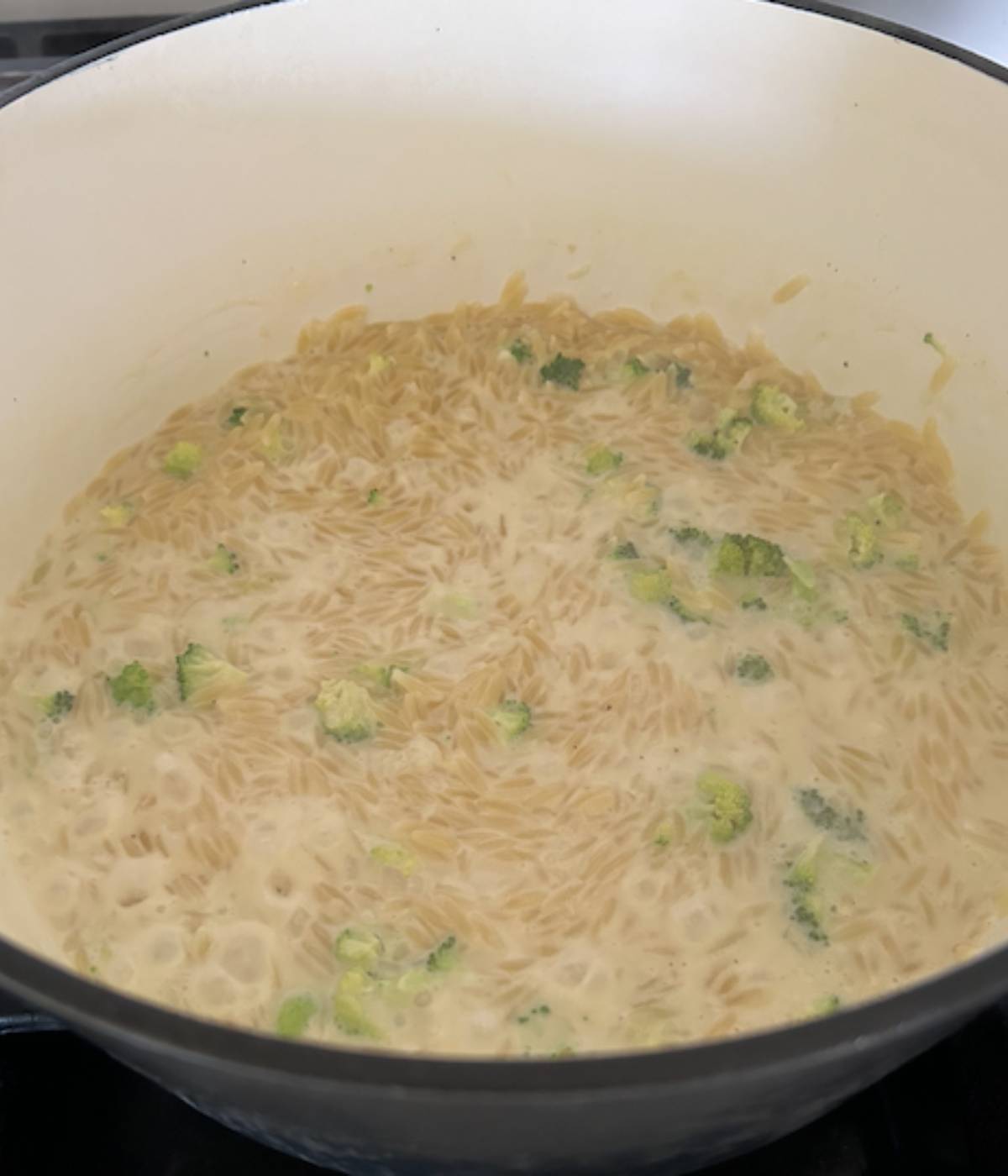 Broccoli orzo cooking in pot.