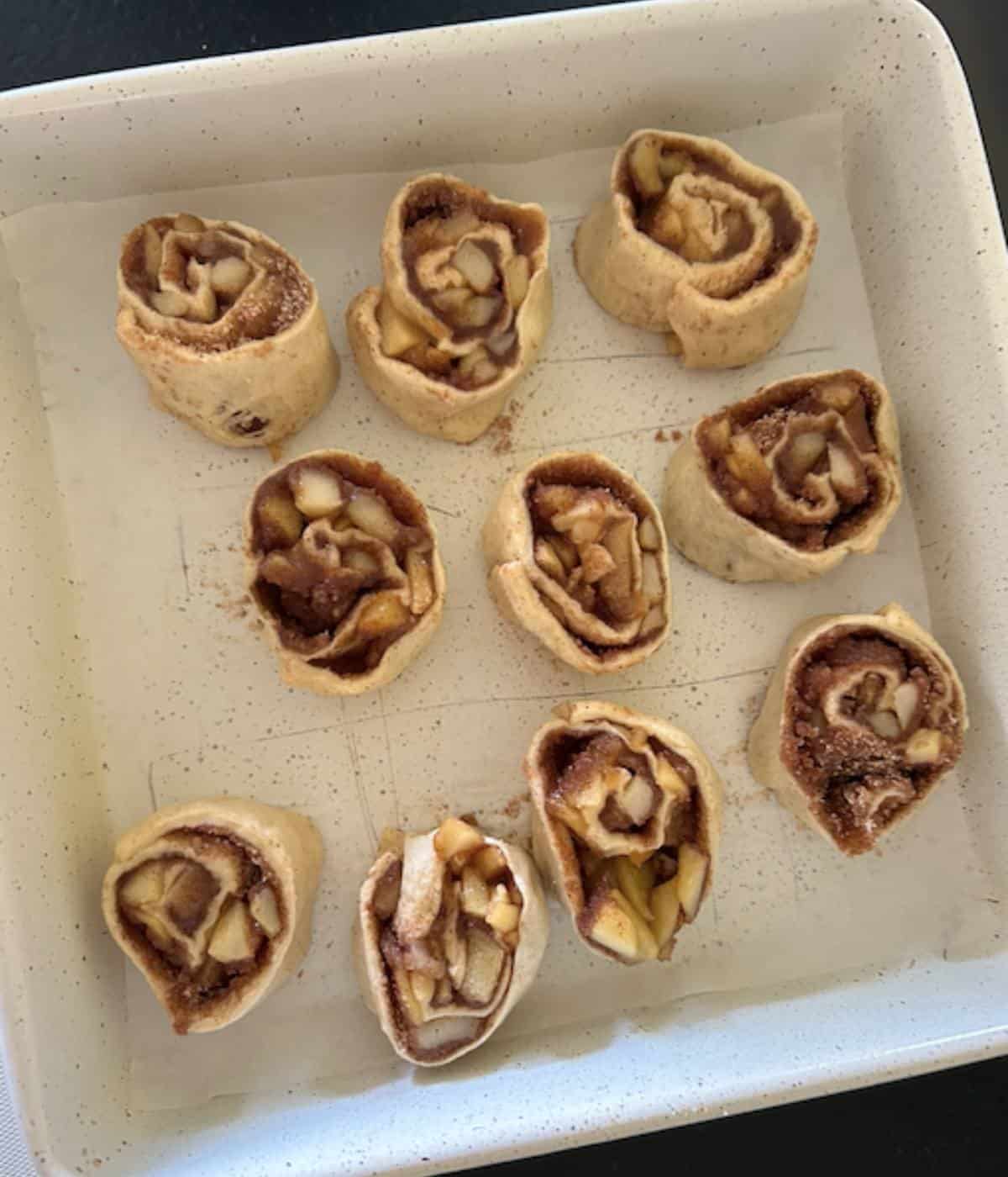 Raw cinnamon rolls in baking dish.