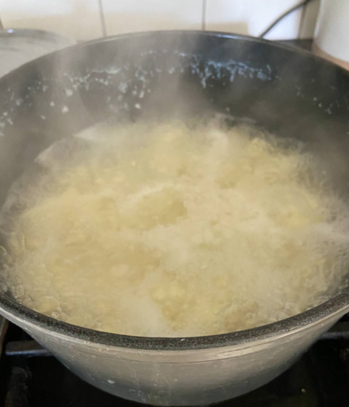 Potatoes boiling in water in pot.