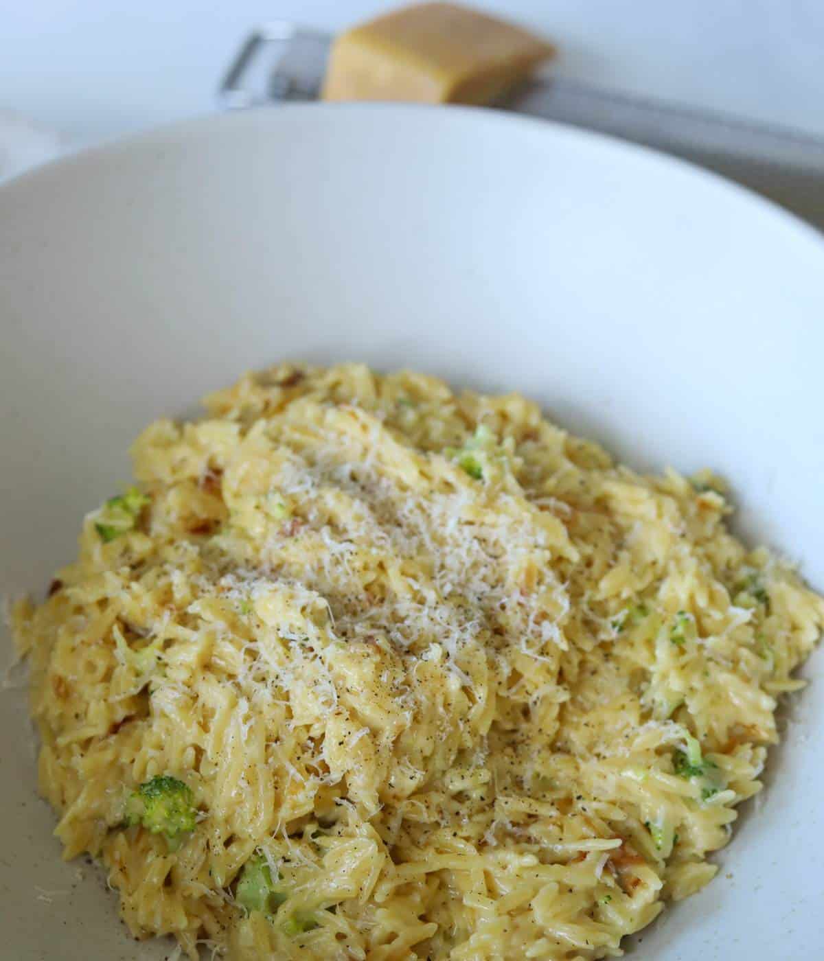 Broccoli orzo in white bowl topped with parmesan.
