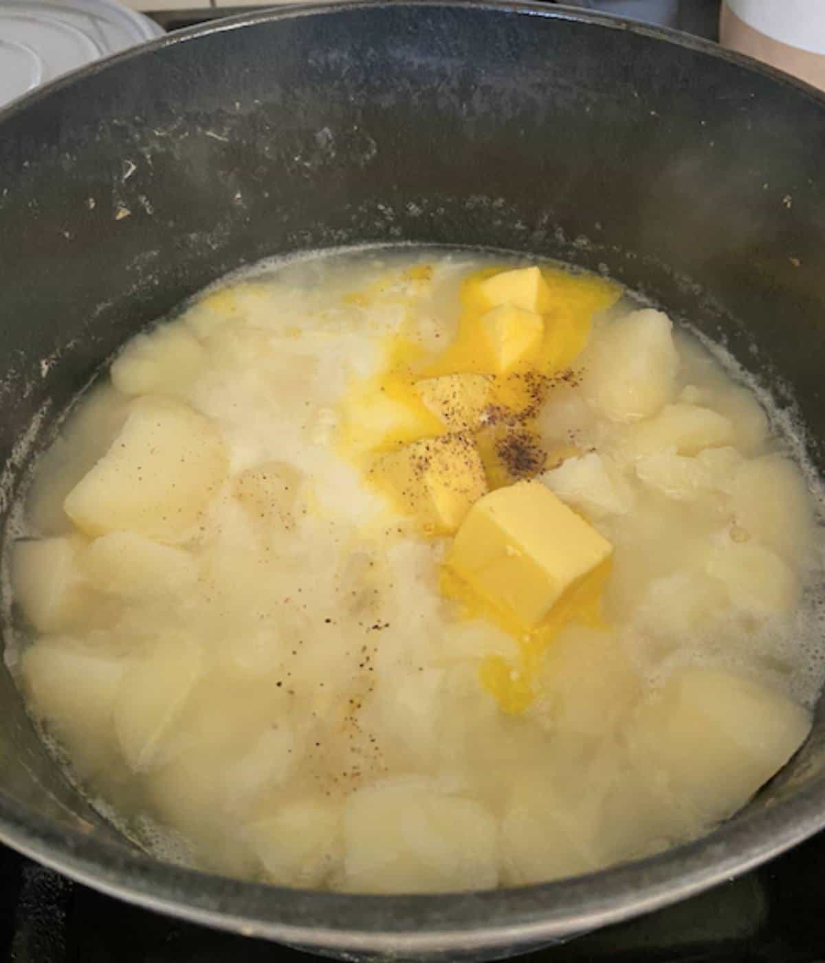 Stewed potatoes with butter, salt and pepper in dutch oven.