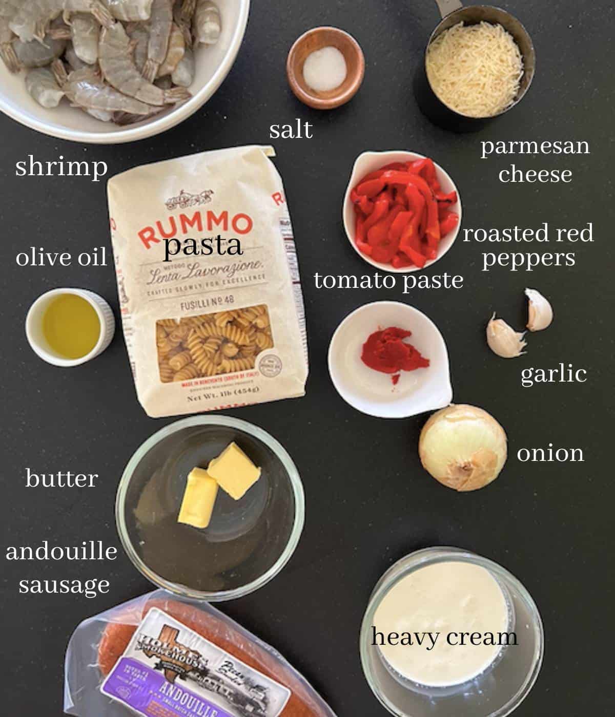 Ingredients for cajun pasta on black countertop.