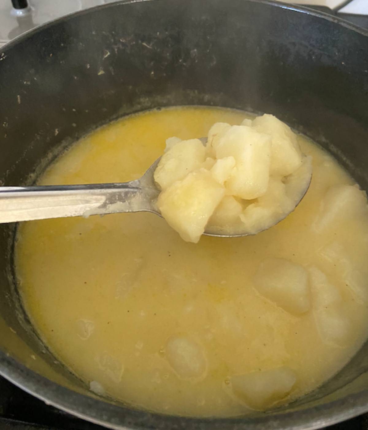 Spoon holding stewed potatoes.