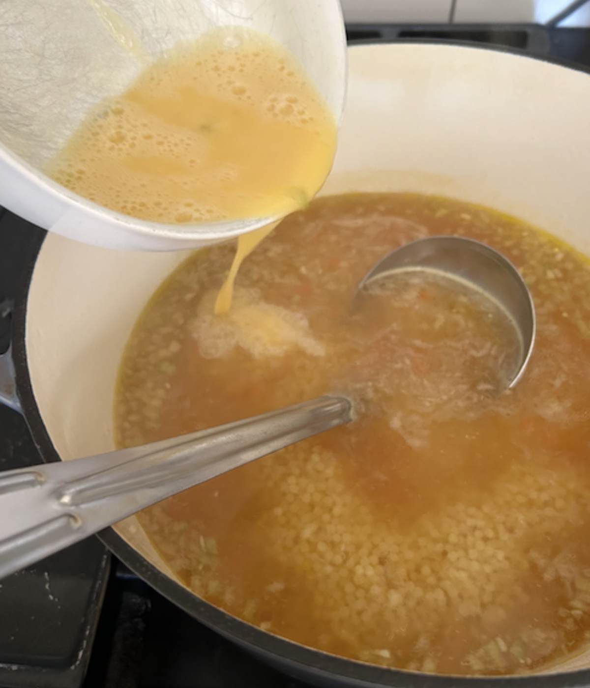 Pouring egg into pastina soup.