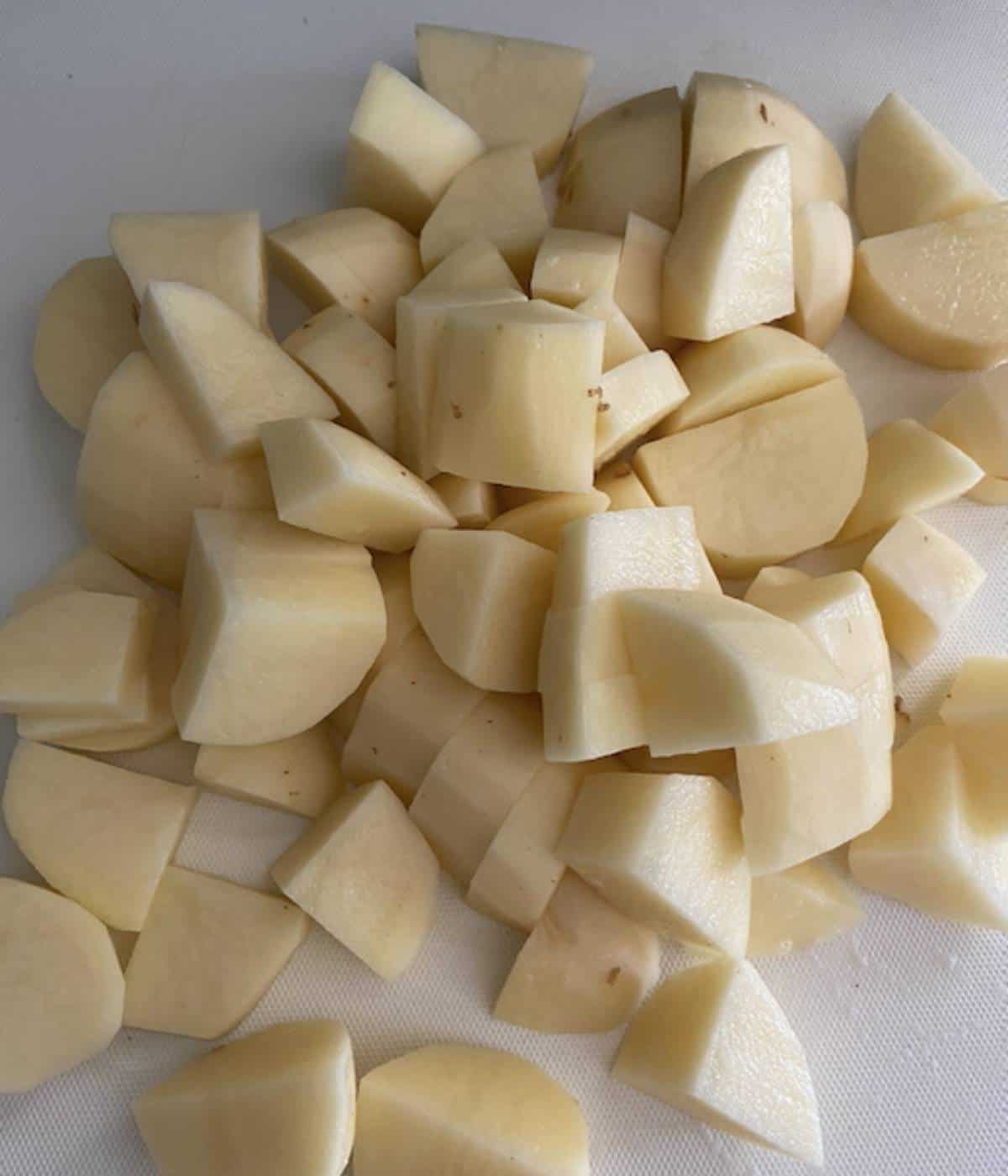 Peeled and cubed russet potatoes on cutting board.