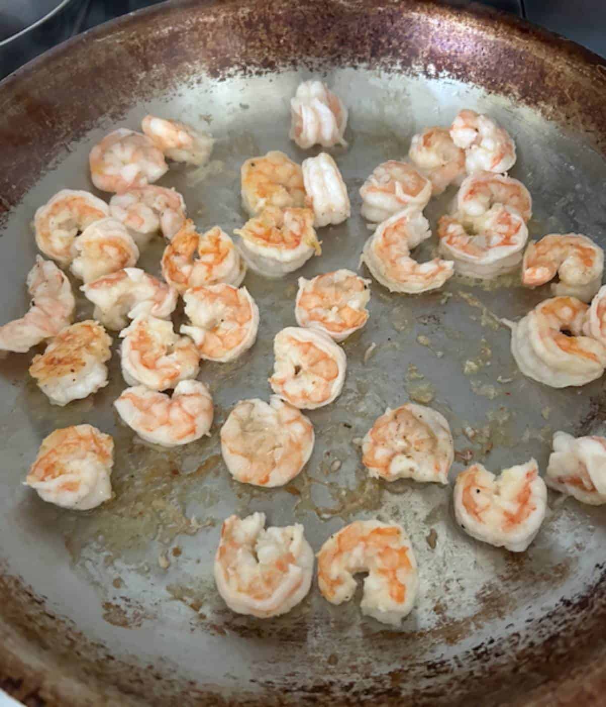 Shrimp cooking in stainless steel pan.