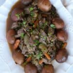 Sirloin roast with onions, carrots, potatoes and gravy on serving dish.