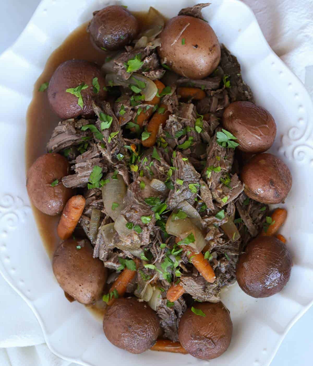 Sirloin roast with onions, carrots, potatoes and gravy on serving dish. 