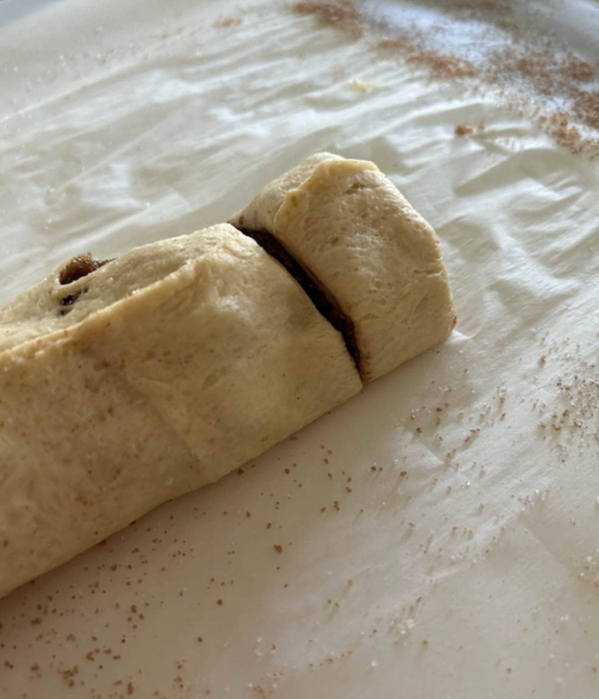 Sliced cinnamon roll on parchment paper.