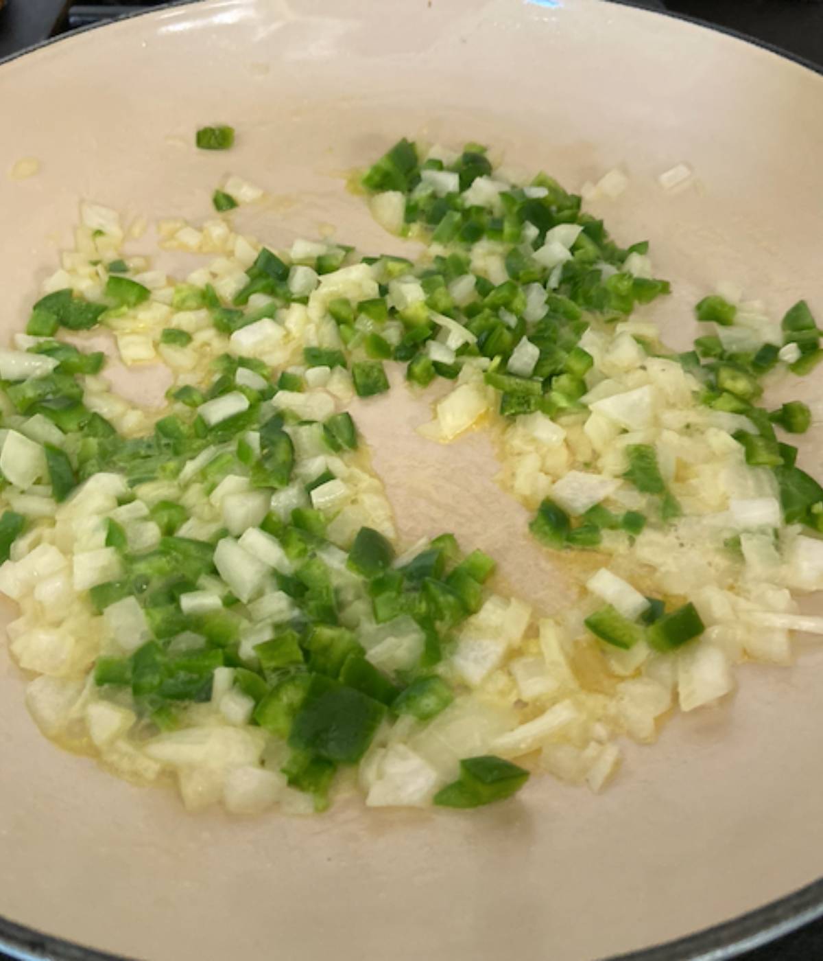 Jalapeno peppers and onions cooking in skillet.
