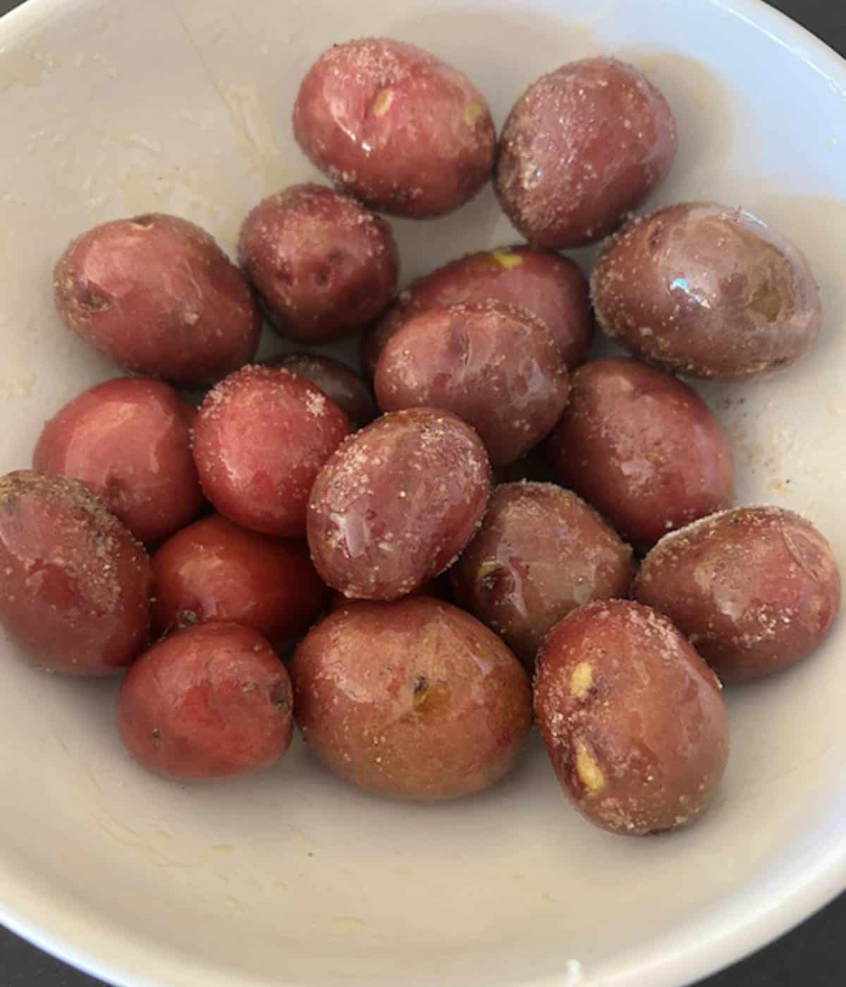 Bite size potatoes in bowl with olive oil salt and pepper.